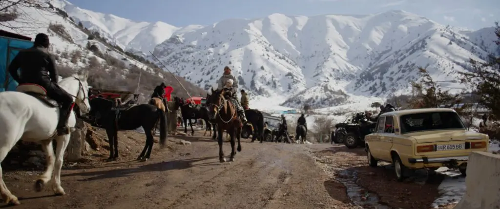 Ruiters met paarden en een oude Lada aan de voet van een skigebied in Oezbekistan